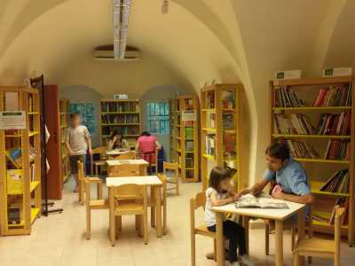 L'ampio ambiente interno della biblioteca: sulla destra una bambina sfoglia un libro accanto al pap�